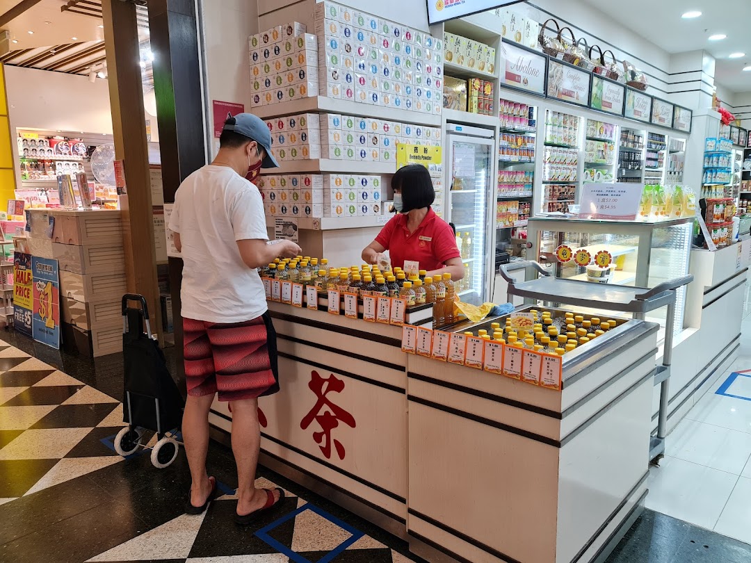A customer interacts with staff at a counter displaying traditional tonic drinks and health products.