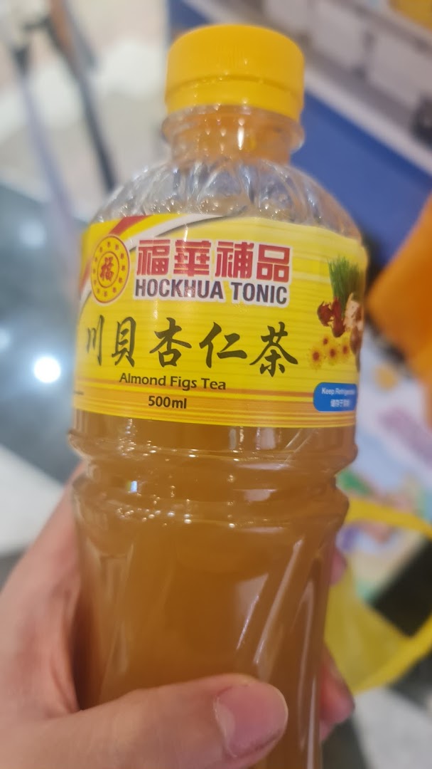 A hand holds a bottle of Hockhua Tonic Almond Figs Tea, showing the product label.