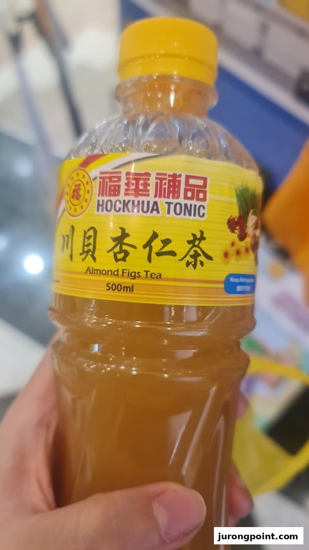 A hand holds a bottle of Hockhua Tonic Almond Figs Tea, showing the product label.