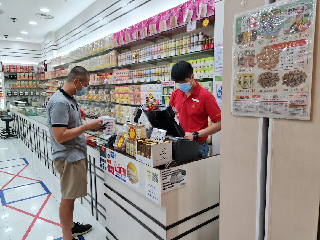 Inside Hockhua Tonic, a customer interacts with staff at the counter amidst shelves stocked with traditional health products.