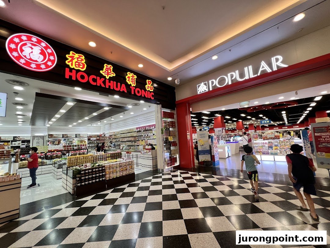 The brightly lit entrance of Hockhua Tonic, showcasing traditional wellness products, next to Popular bookstore.