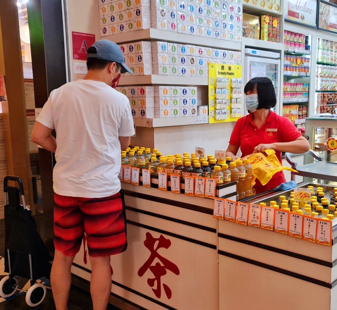 A customer interacts with a staff member at a counter displaying various bottled tonics and traditional remedies.
