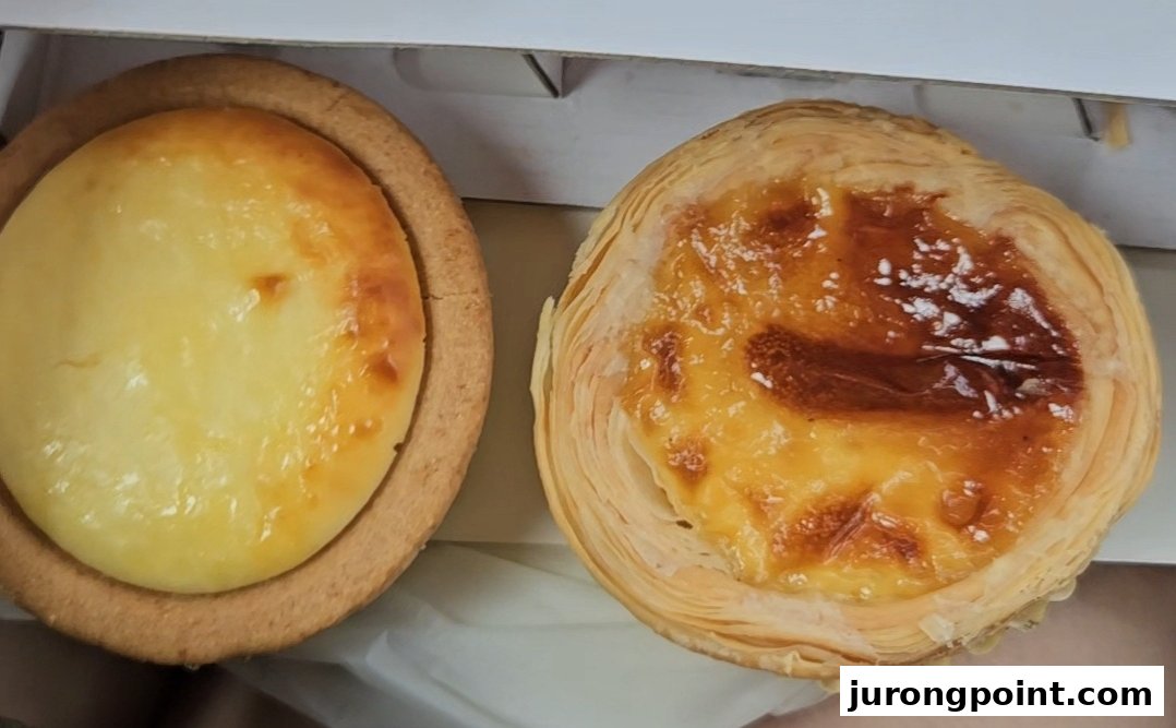 Close-up of a Hokkaido Baked Cheese Tart and a Portuguese egg tart in a box.