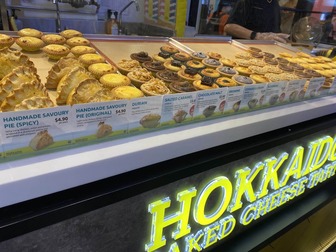 A vibrant display counter showcasing a variety of delicious tarts and pies with visible pricing.