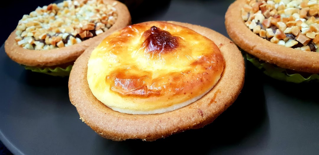 Close-up of a golden-brown Hokkaido Baked Cheese Tart with other tarts in the background.