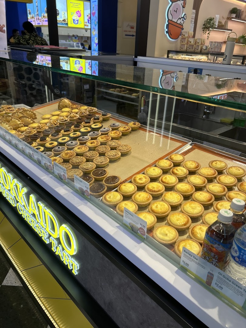A vibrant display case showcasing a variety of freshly baked cheese tarts and other pastries.