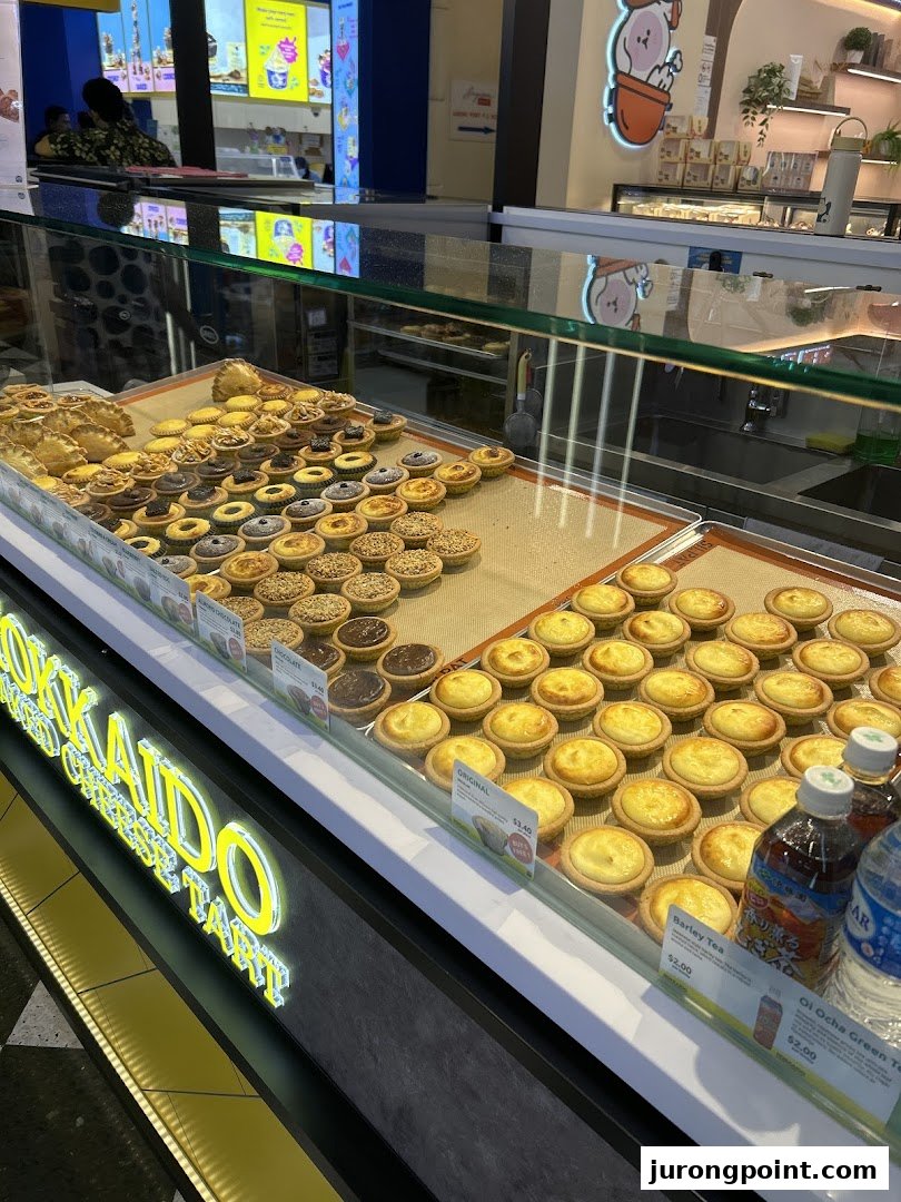 A vibrant display case showcasing a variety of freshly baked cheese tarts and other pastries.