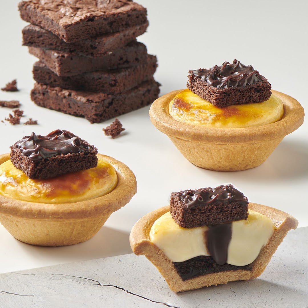 Delicious cheese tarts topped with brownies, alongside a stack of rich chocolate brownies.