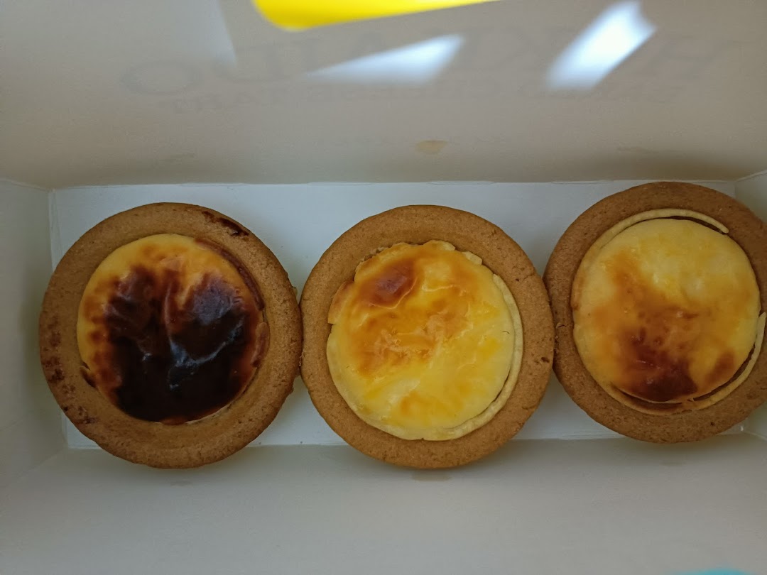Three delicious Hokkaido Baked Cheese Tarts with golden-brown tops in a white box.