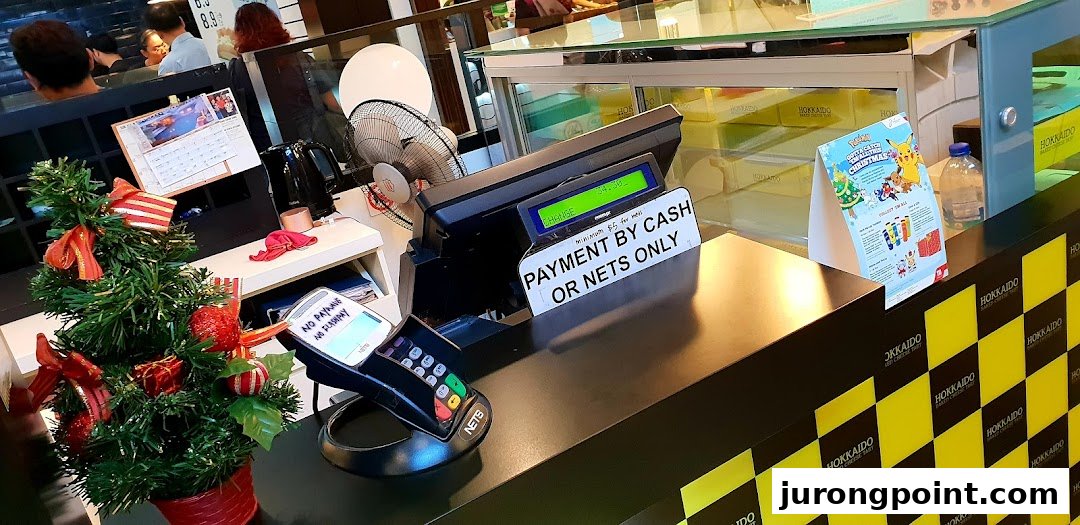 A festive counter at Hokkaido Baked Cheese Tart, featuring a payment terminal, Christmas decor, and branded packaging.