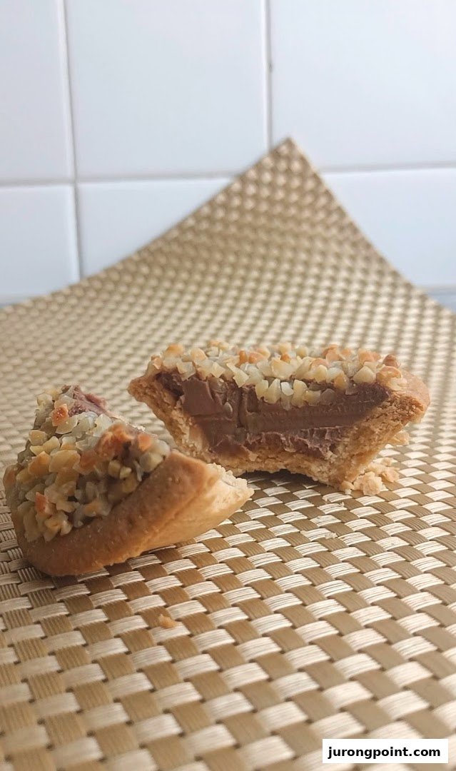 A delicious tart, cut in half, revealing a rich chocolate or caramel filling and a crunchy nut topping.