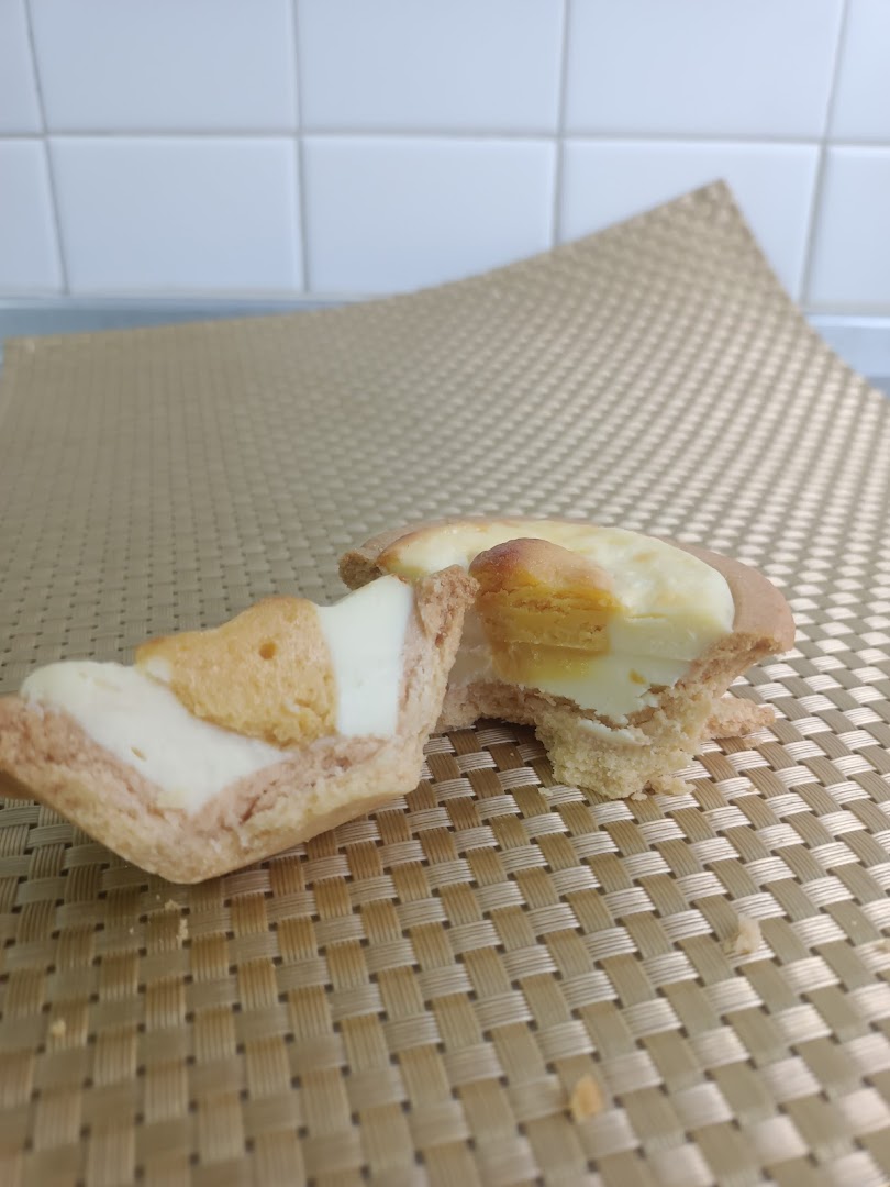 A Hokkaido Baked Cheese Tart, broken in half, revealing its creamy filling and golden crust.