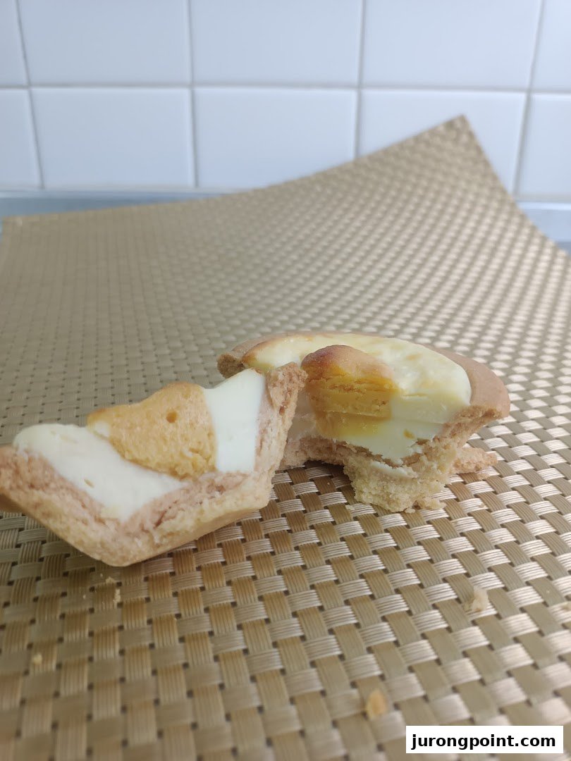 A Hokkaido Baked Cheese Tart, broken in half, revealing its creamy filling and golden crust.