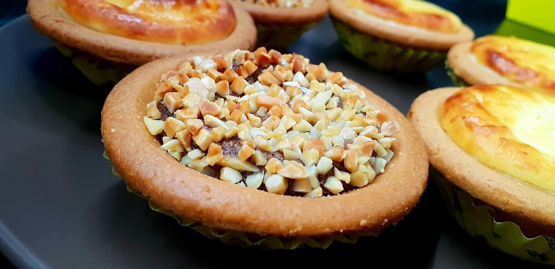 Close-up of various Hokkaido Baked Cheese Tarts, including a chocolate and nut flavor.