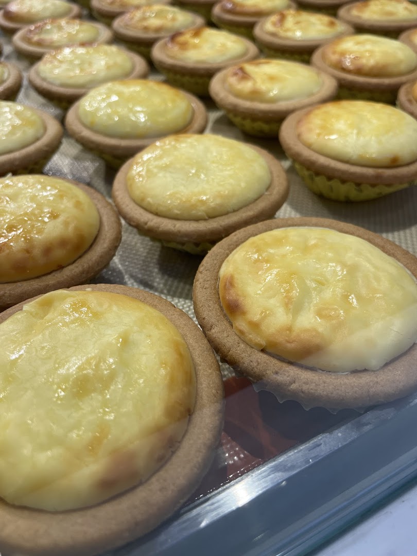 Rows of golden-baked cheese tarts displayed in a retail setting.