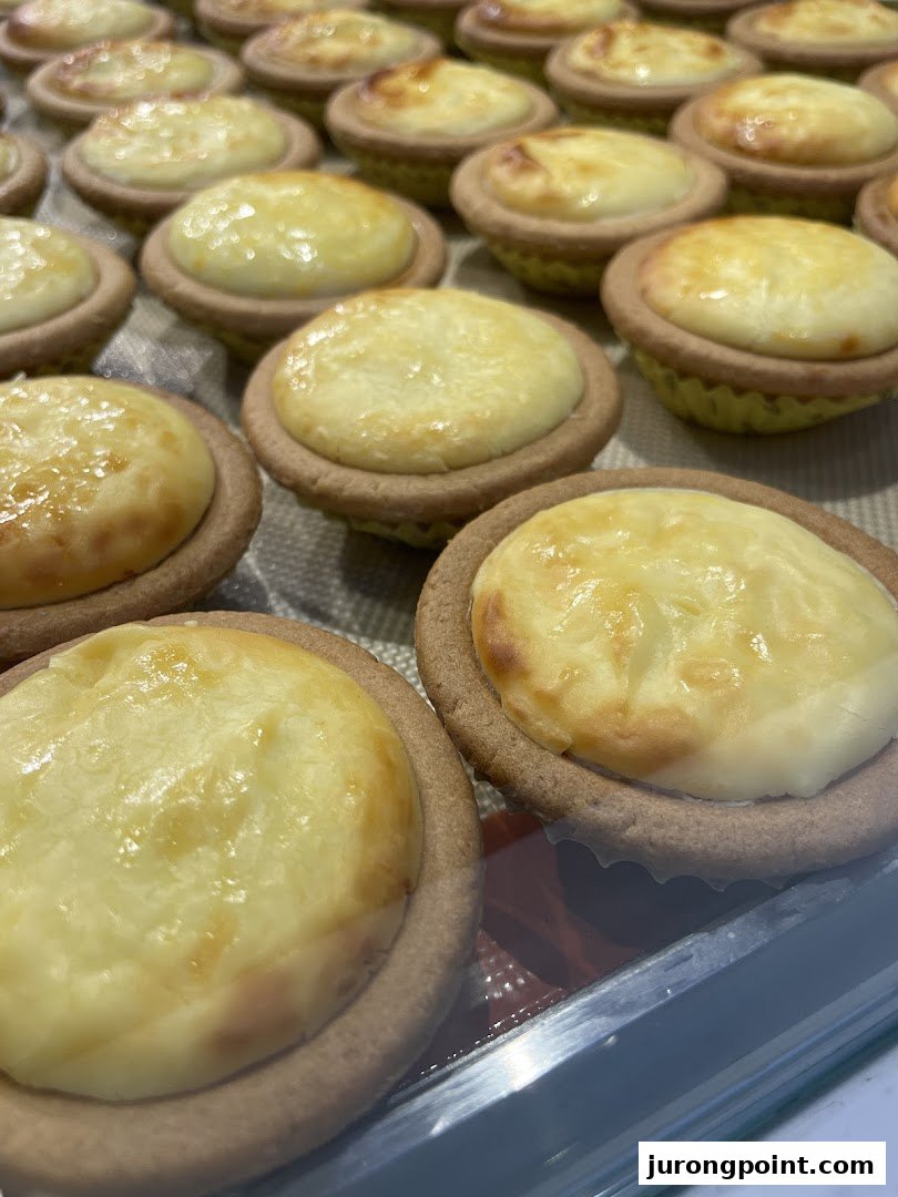 Rows of golden-baked cheese tarts displayed in a retail setting.