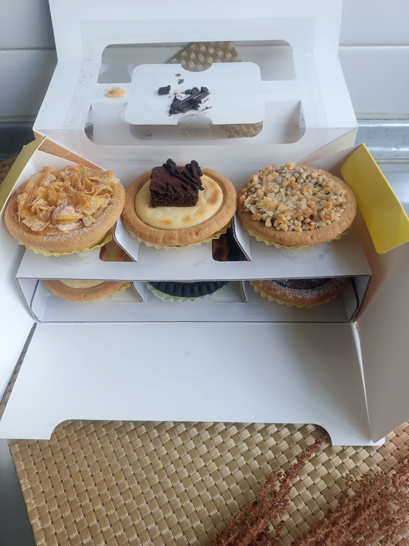 A box of assorted Hokkaido Baked Cheese Tarts with various toppings, including cornflakes, brownie, and nuts.