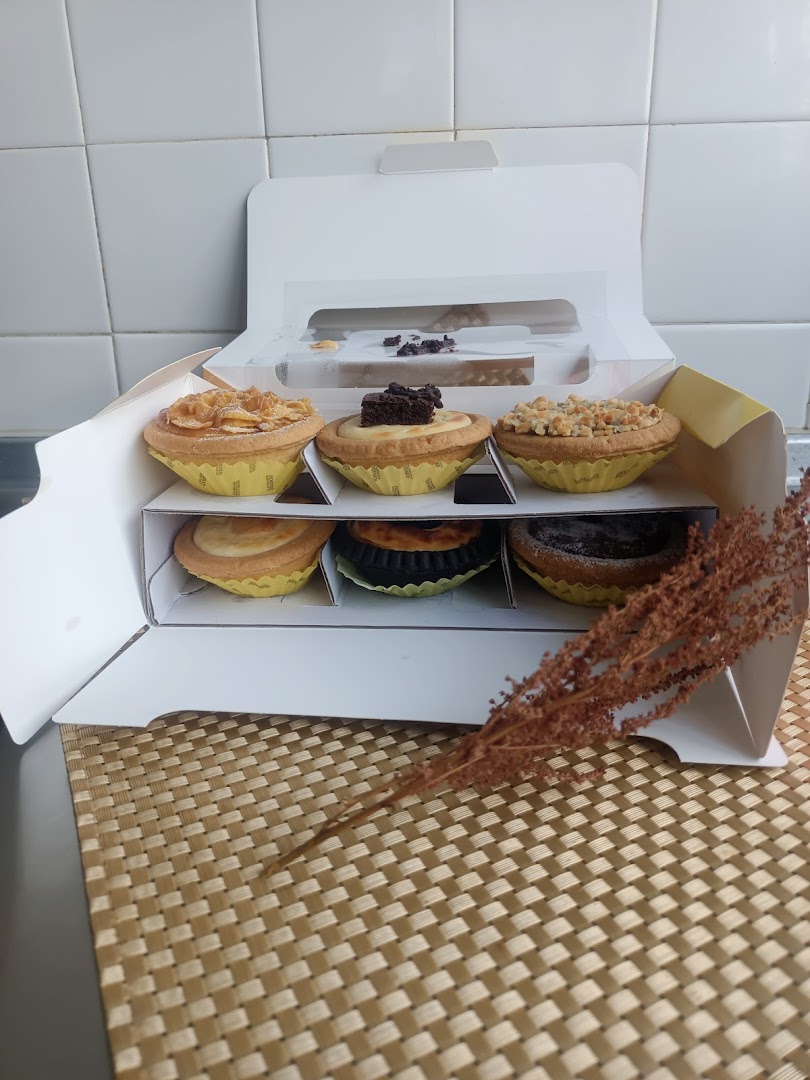 A white box containing six assorted Hokkaido Baked Cheese Tarts on a woven mat.