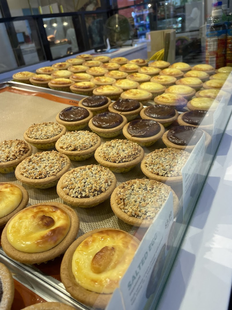 A vibrant display of freshly baked tarts, including cheese, chocolate, and nut-topped varieties.