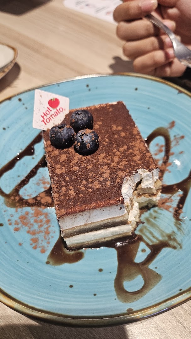 A delicious tiramisu-like dessert topped with blueberries and cocoa powder on a blue plate.
