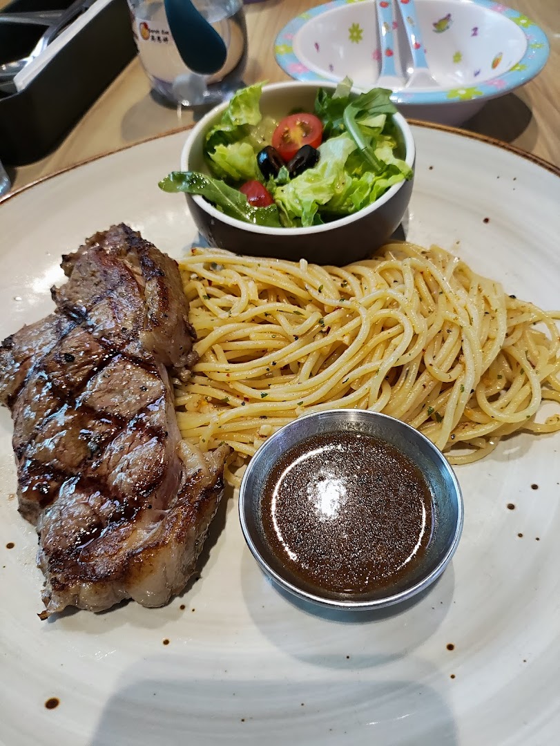 A delicious plate featuring grilled steak, spaghetti, a fresh side salad, and sauce.