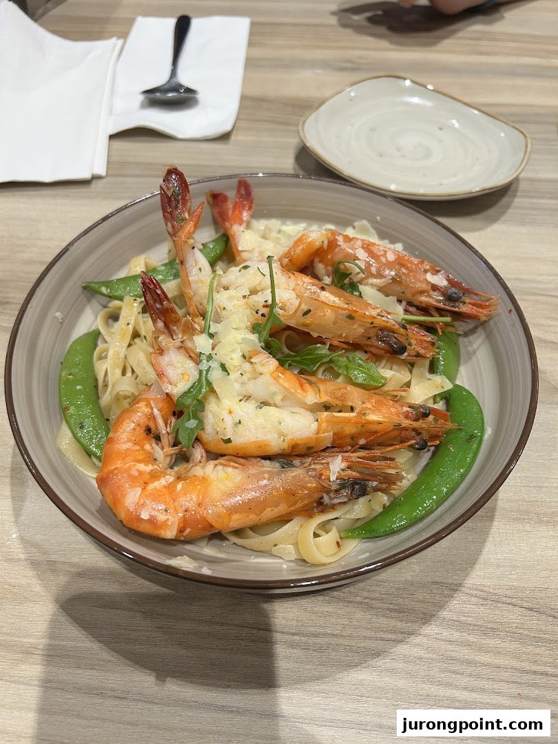 A delicious plate of creamy pasta with large prawns, snow peas, and grated cheese.