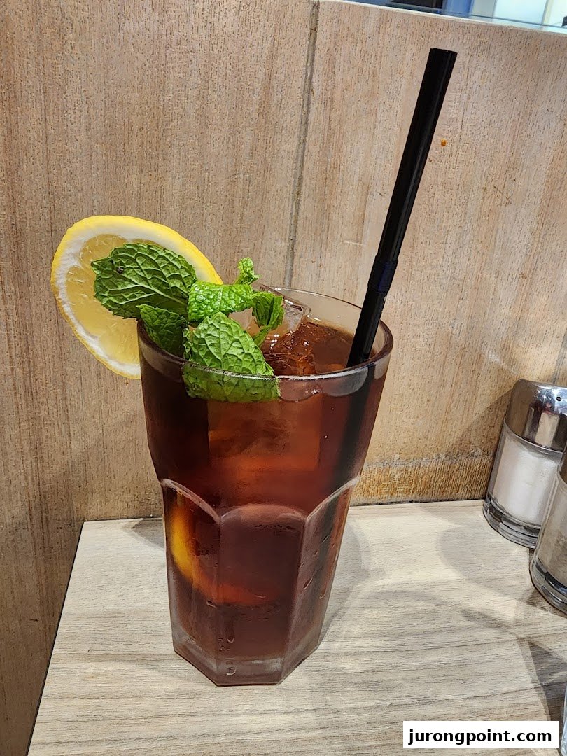 A refreshing iced tea with lemon and mint garnish on a wooden table.