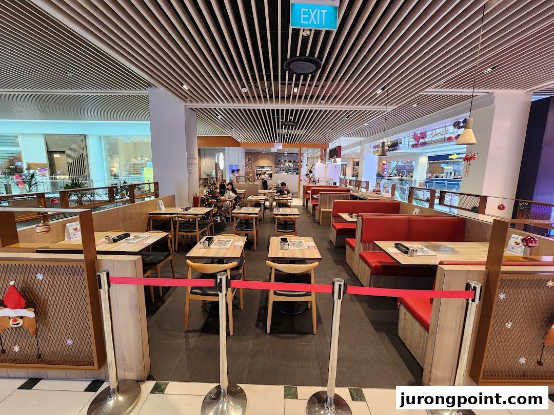 Spacious interior of Hot Tomato restaurant featuring dining tables, red booths, and festive decor.