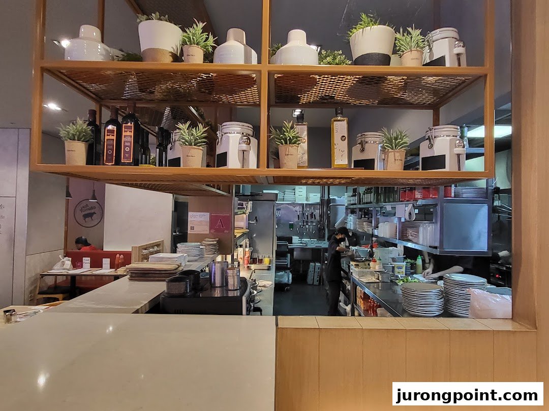 An interior view of Hot Tomato, showcasing its open kitchen, counter, and decorative shelving.