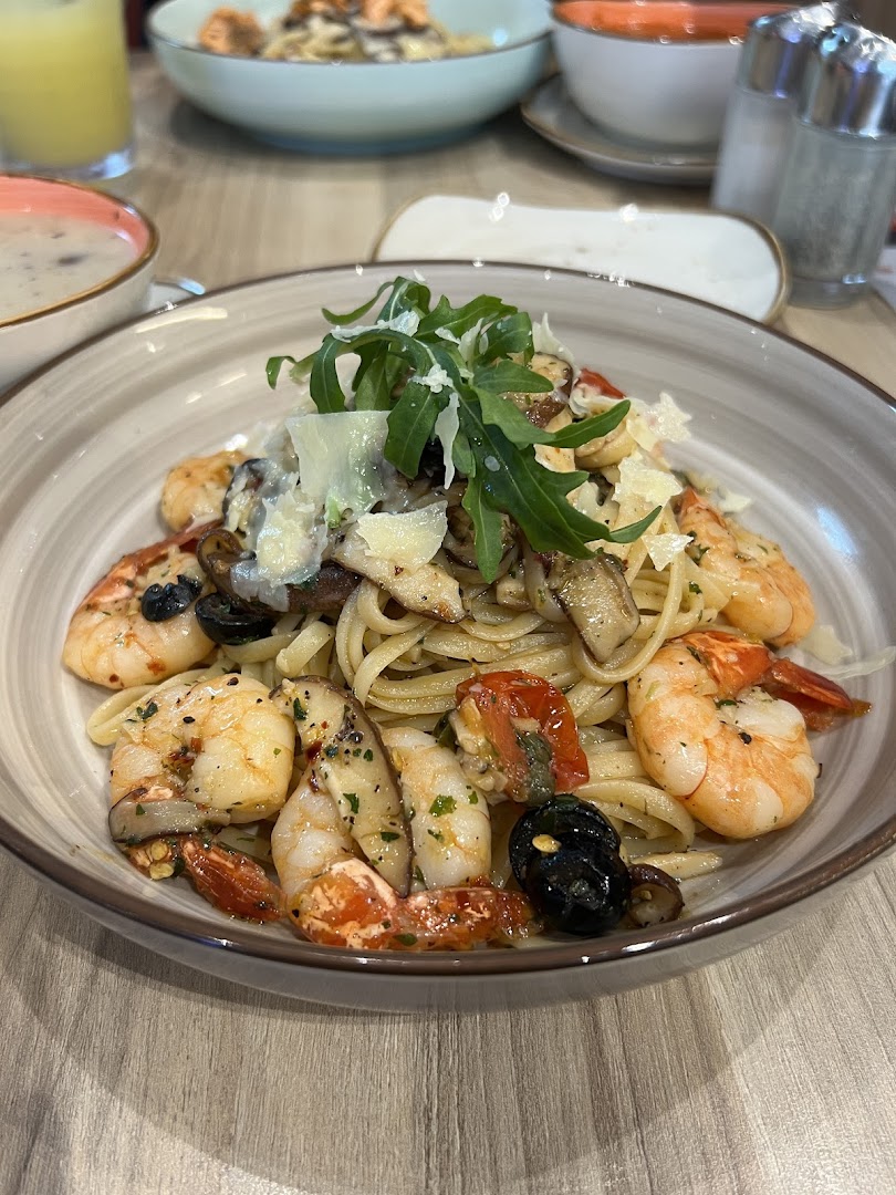 A close-up of a delicious pasta dish with shrimp, mushrooms, and arugula.