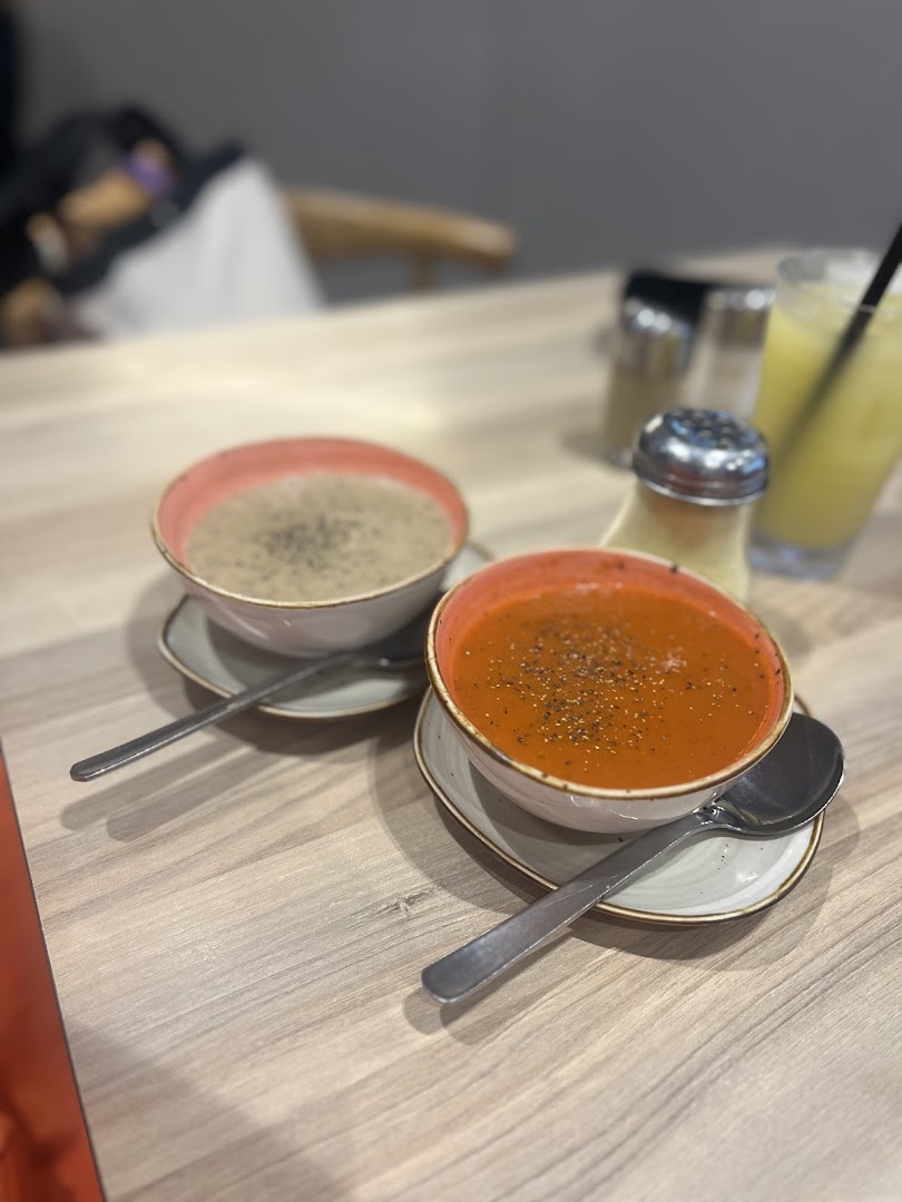Two bowls of delicious soup, one tomato and one creamy, served on a wooden table.