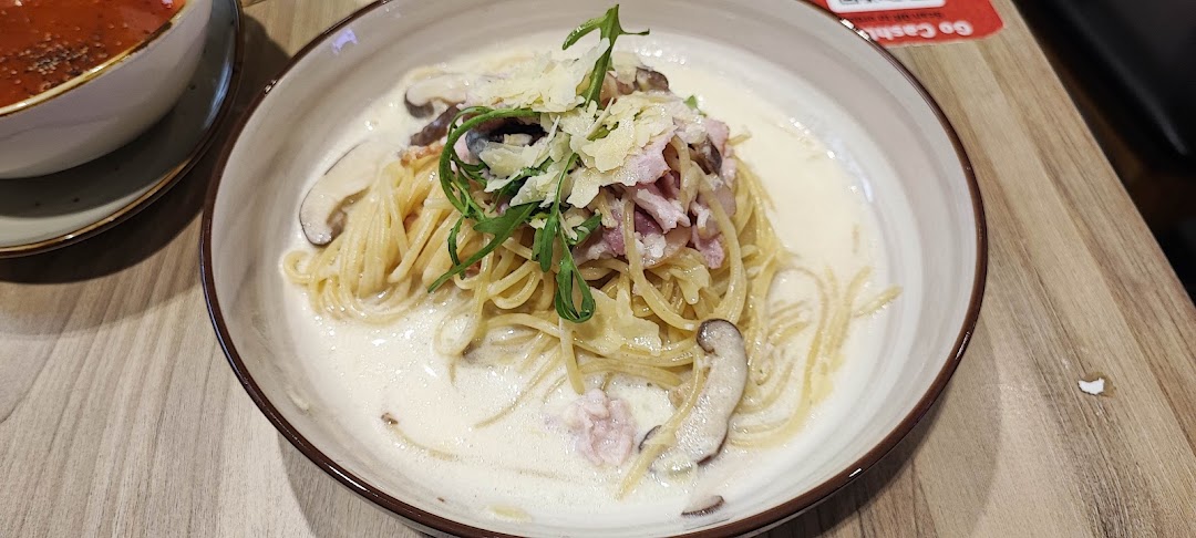 A creamy pasta dish with mushrooms, bacon, and parmesan cheese in a bowl.