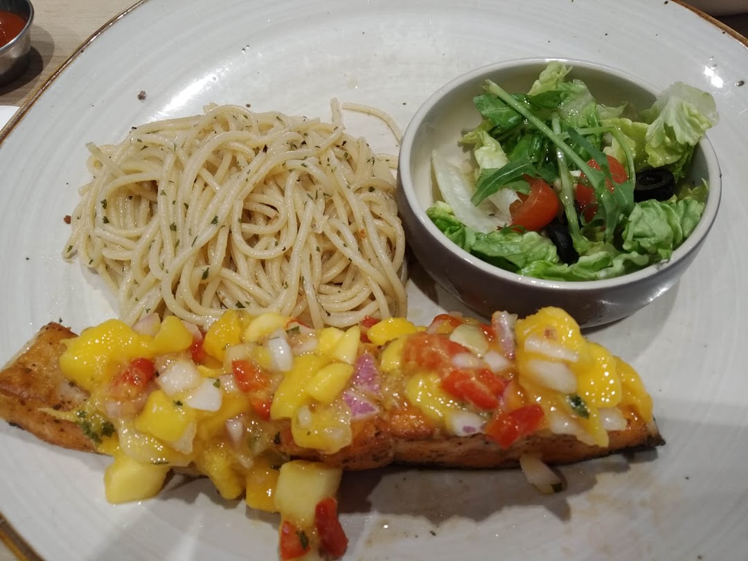 A plate featuring pan-seared fish with mango salsa, spaghetti, and a fresh side salad.