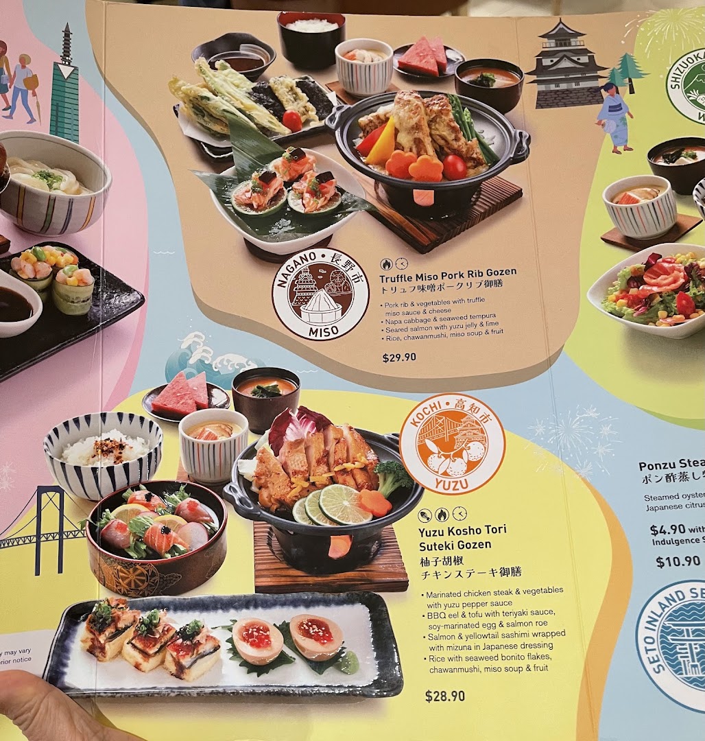 A close-up of a Japanese restaurant menu displaying various set meals and side dishes with descriptions and prices.