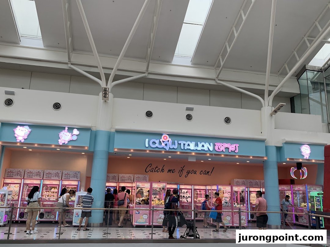 The storefront of iClaw Taiwan, featuring numerous claw machines and people playing them.