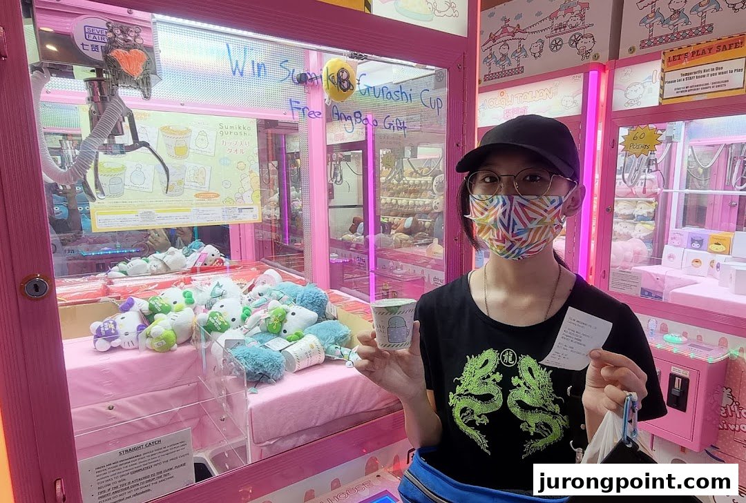 A person holds a prize and receipt in front of pink claw machines filled with plush toys at iClaw Taiwan.