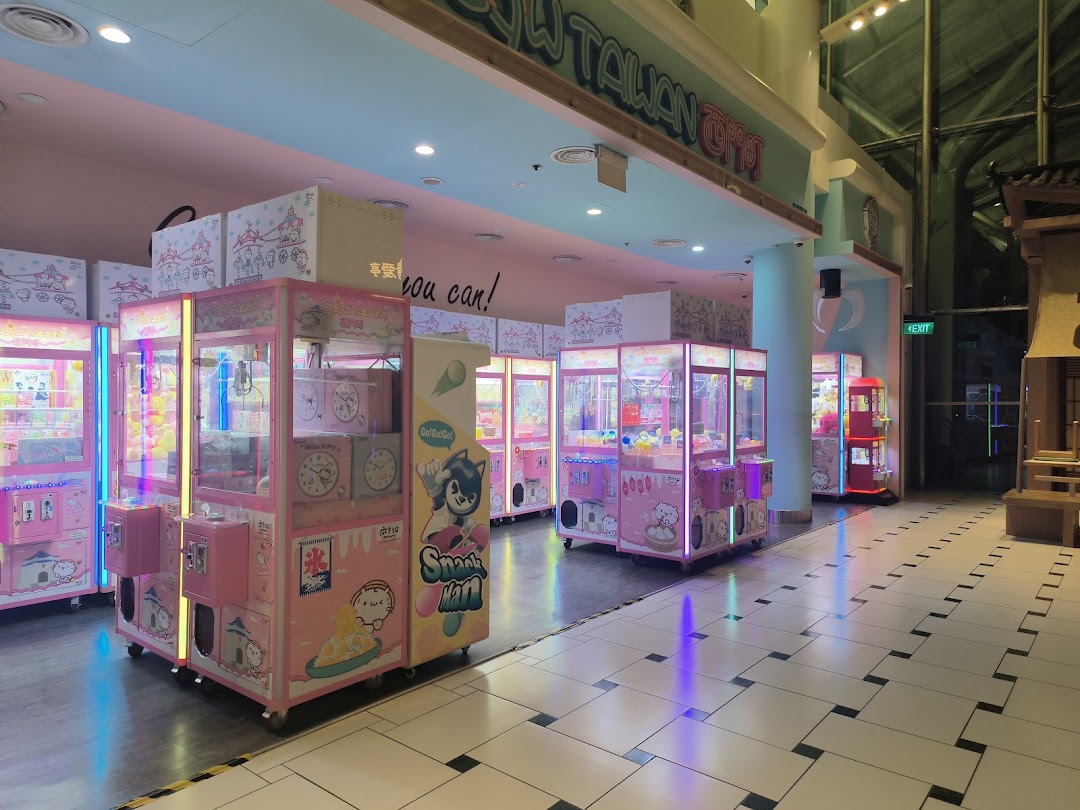 A vibrant arcade space filled with numerous pink claw machines offering various prizes.