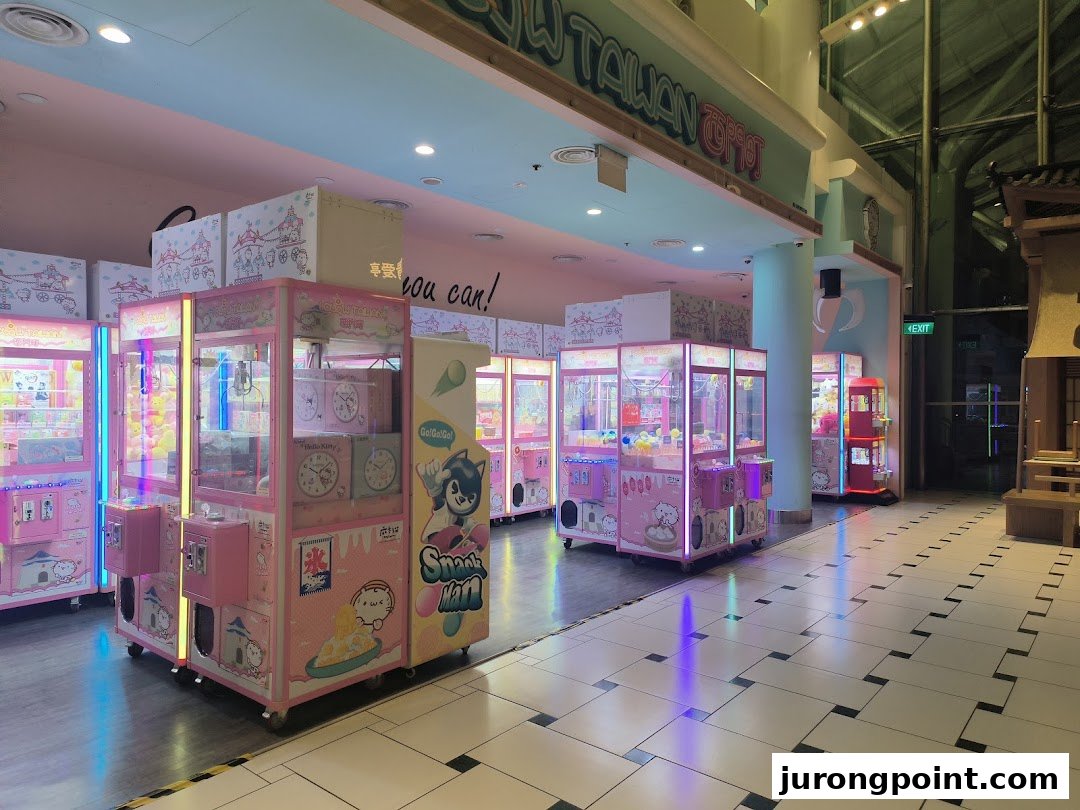 A vibrant arcade space filled with numerous pink claw machines offering various prizes.