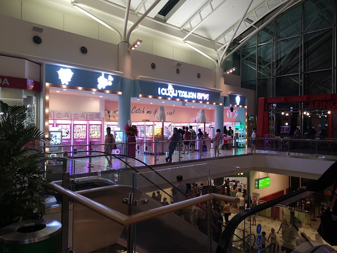 Brightly lit iClaw Taiwan claw machine arcade entrance with people playing, viewed from a mall escalator.
