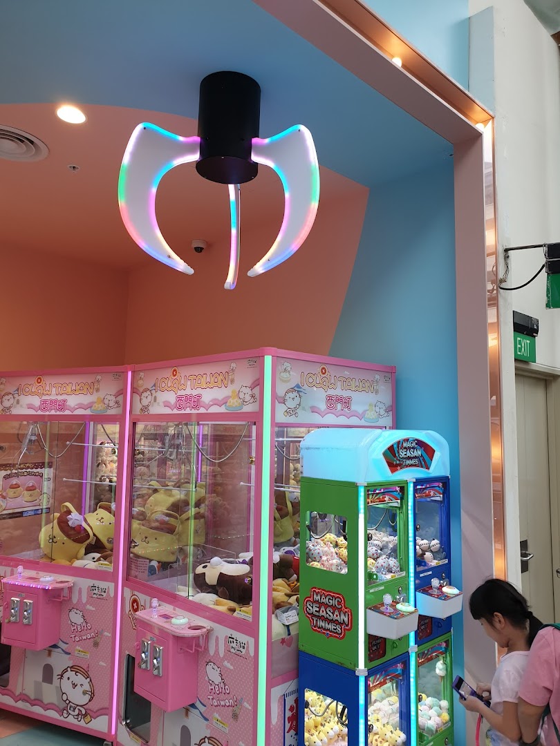 Colorful claw machines filled with plush toys, a decorative claw light, and a customer in a vibrant arcade setting.