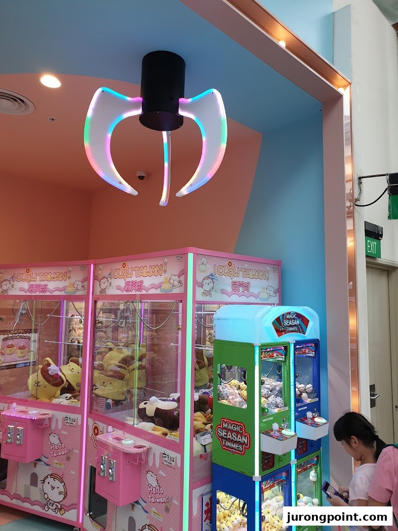Colorful claw machines filled with plush toys, a decorative claw light, and a customer in a vibrant arcade setting.