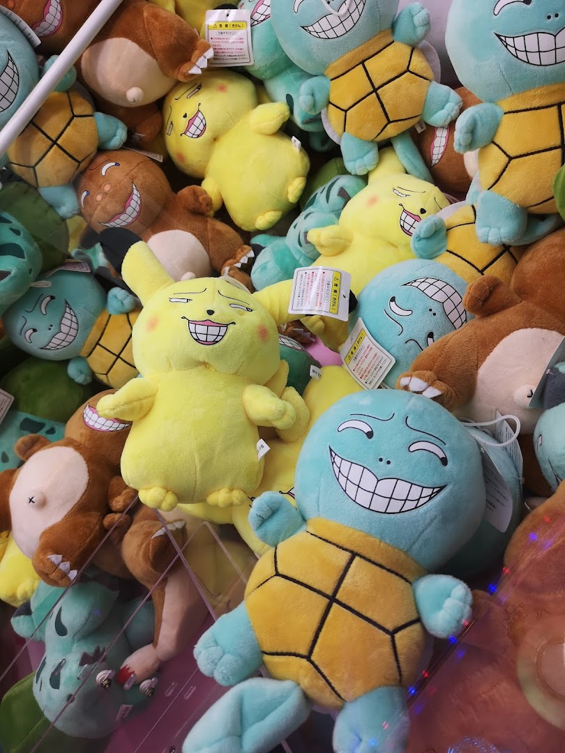 A vibrant collection of quirky plush toys, including turtles and yellow characters, inside a claw machine.