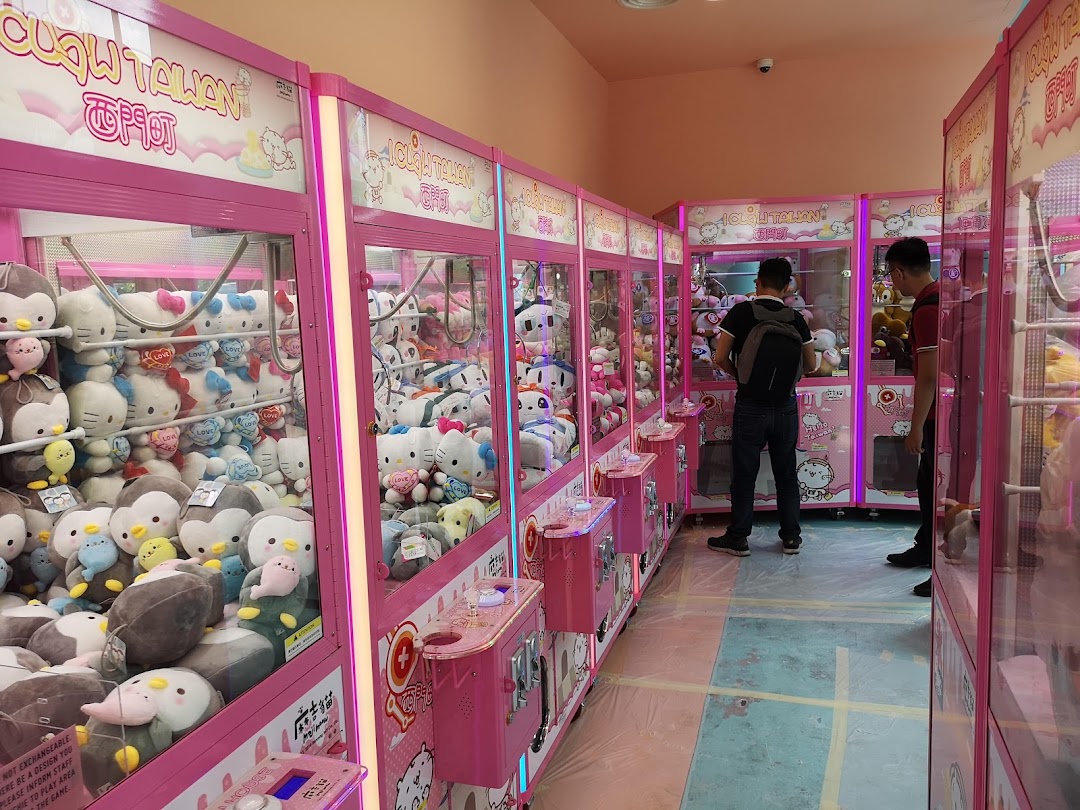 Interior of iClaw Taiwan featuring rows of pink claw machines filled with various plush toys.