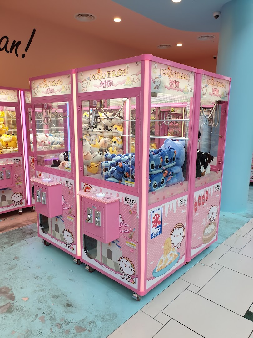 Bright pink claw machines filled with various plush toys line a shop interior.