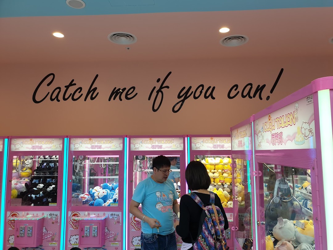 People playing claw machines inside iClaw Taiwan, with a 'Catch me if you can!' slogan on the wall.