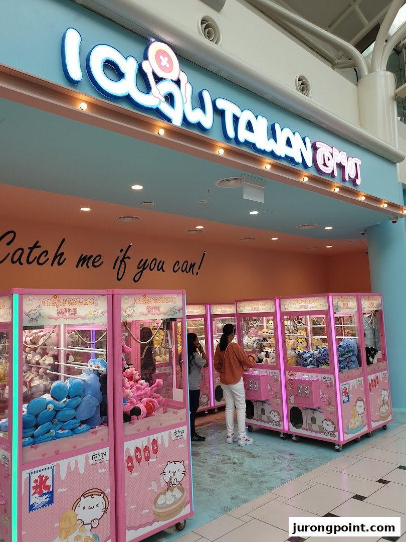 The vibrant pink entrance of iClaw Taiwan, featuring numerous claw machines and customers.