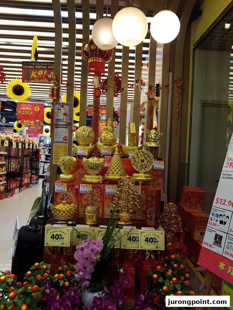 Festive golden decorations and artificial flowers displayed inside a Japan Home store, likely for Chinese New Year.
