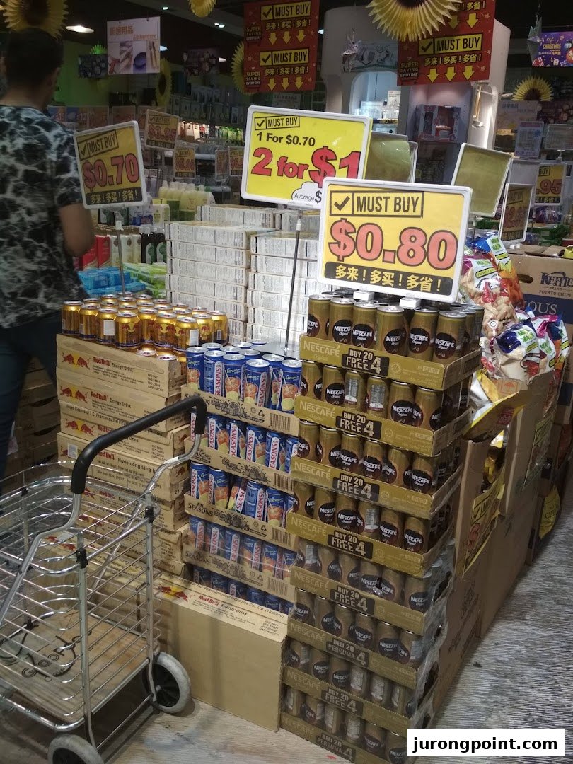 An interior view of Japan Home showcasing stacked beverages, snacks, and prominent 'Must Buy' promotional signs.