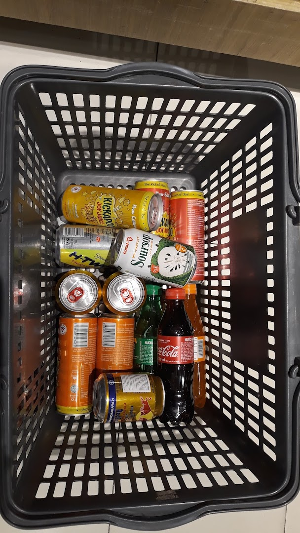 A shopping basket is filled with an assortment of canned and bottled beverages, including juices and soft drinks.