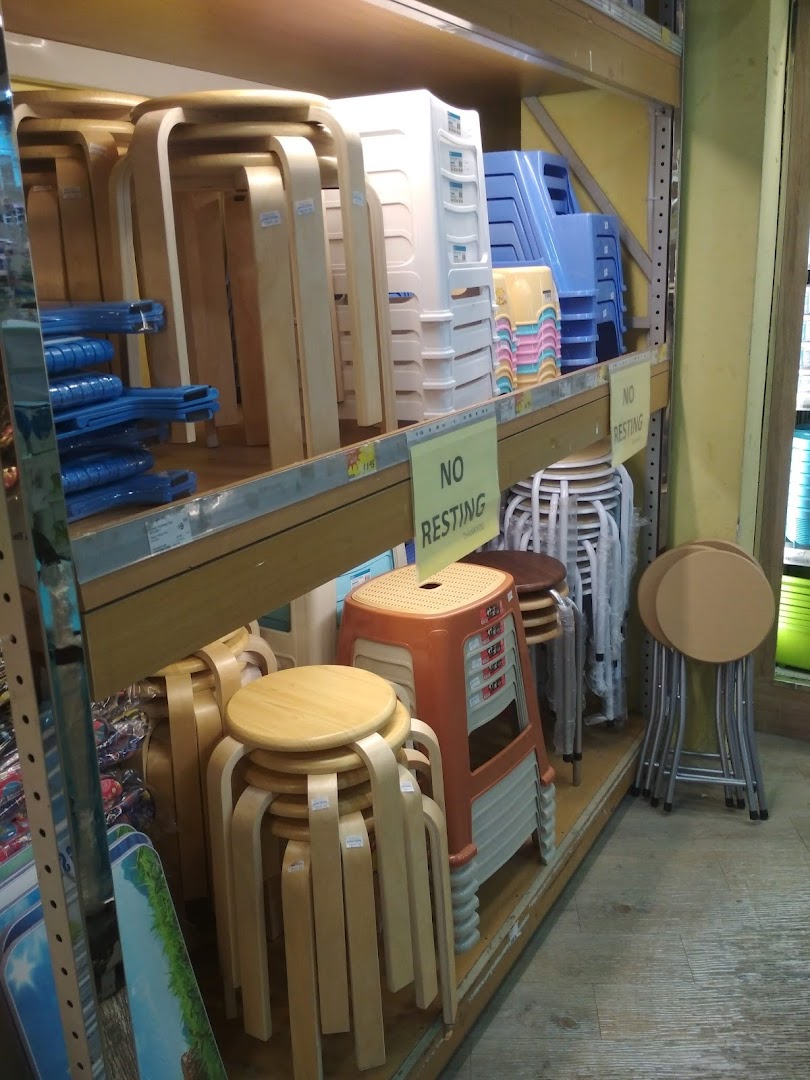 Various types of stools and chairs, including wooden and plastic designs, stacked on shelves in a retail store.